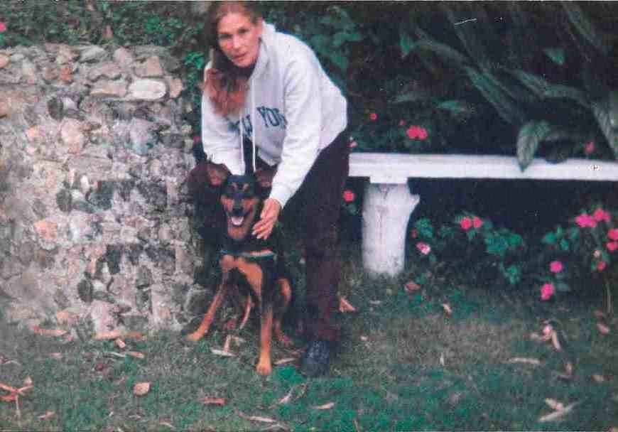 Paisaje con flores, un banco de madera y cesped. A un lado estamos Mickey y yo tratando de estar quietos para la foto.