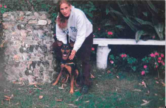 Paisaje con flores, un banco de madera y cesped. A un lado estamos Mickey y yo tratando de estar quietos para la foto.